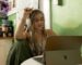 a woman with dreadlocks sitting in front of a laptop computer